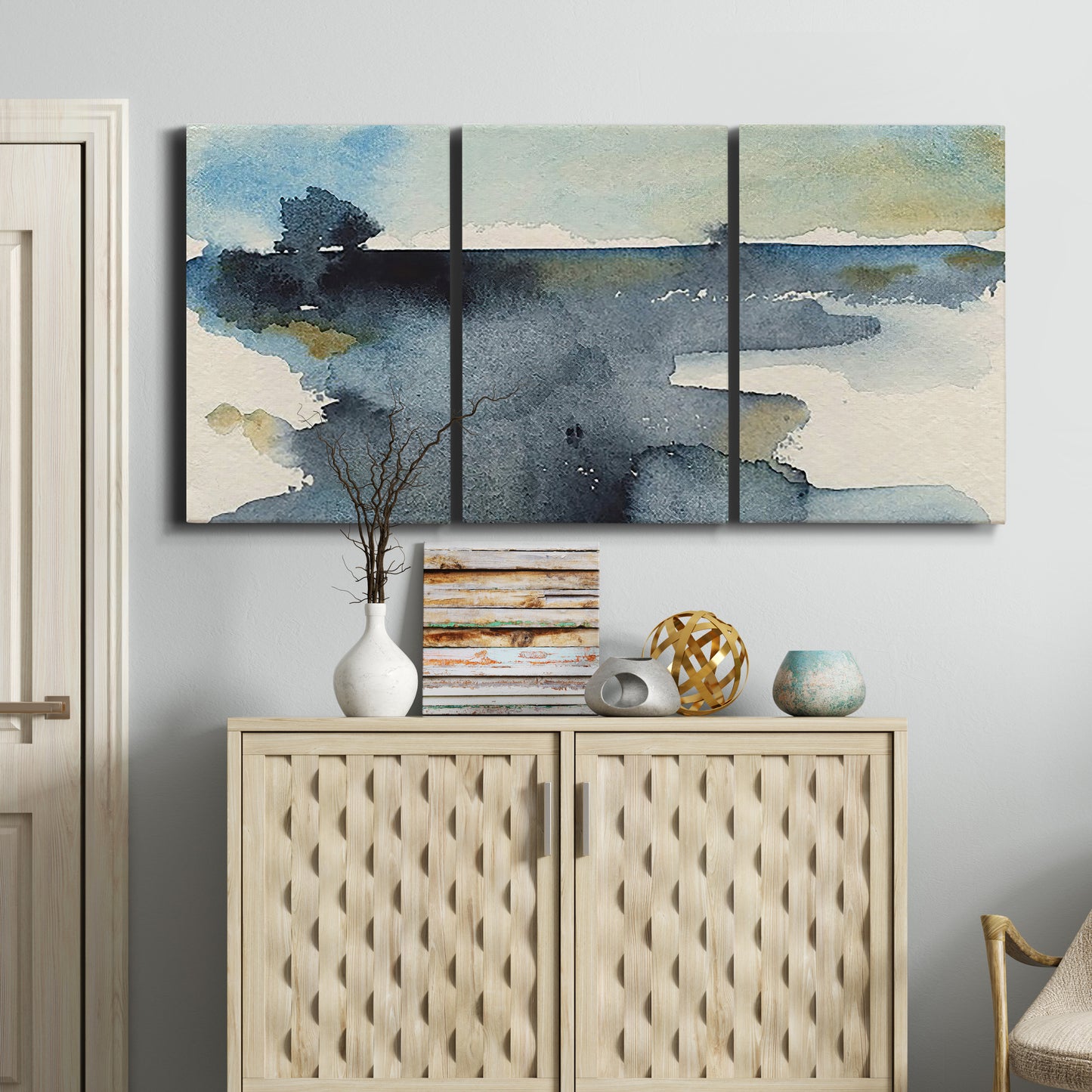 Three-panel canvas wall art featuring abstract watercolor with upward motion, displayed above a cabinet in an entryway.