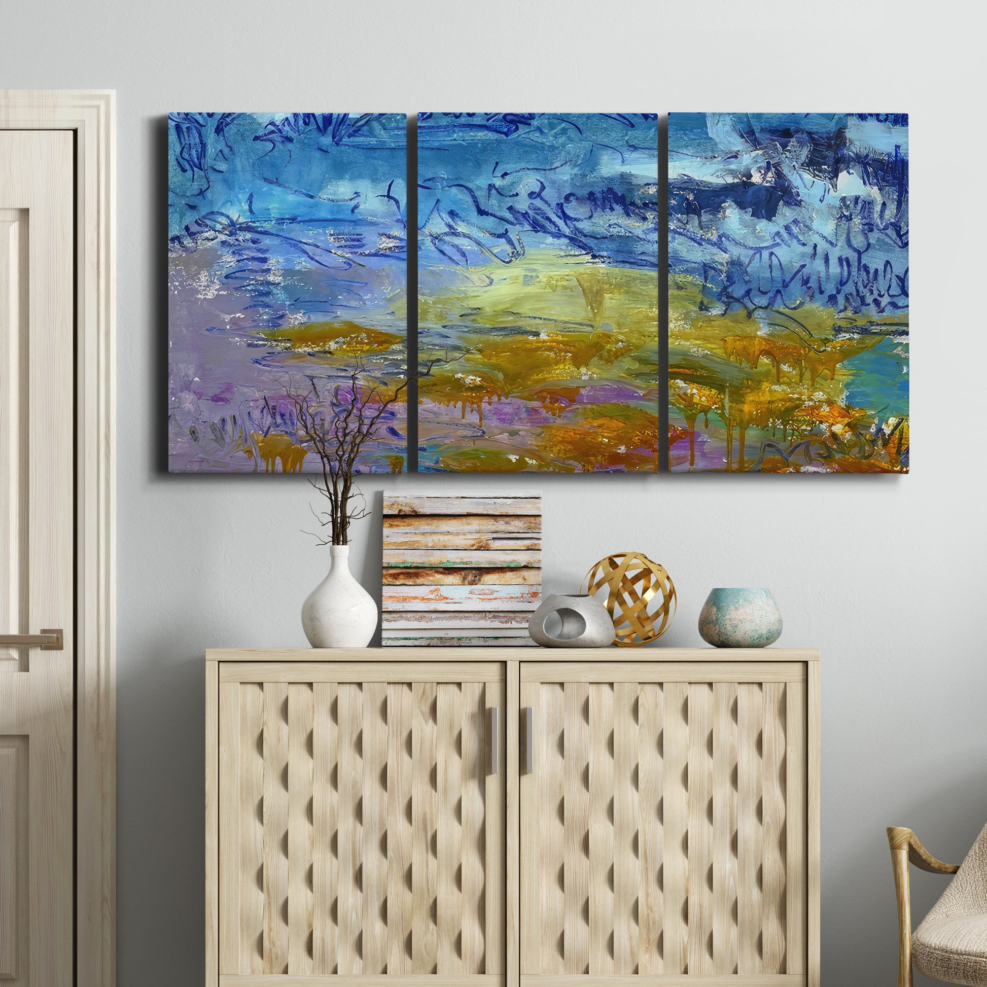 Three-panel canvas wall art featuring expressive abstract with layered color, displayed above a cabinet in an entryway.