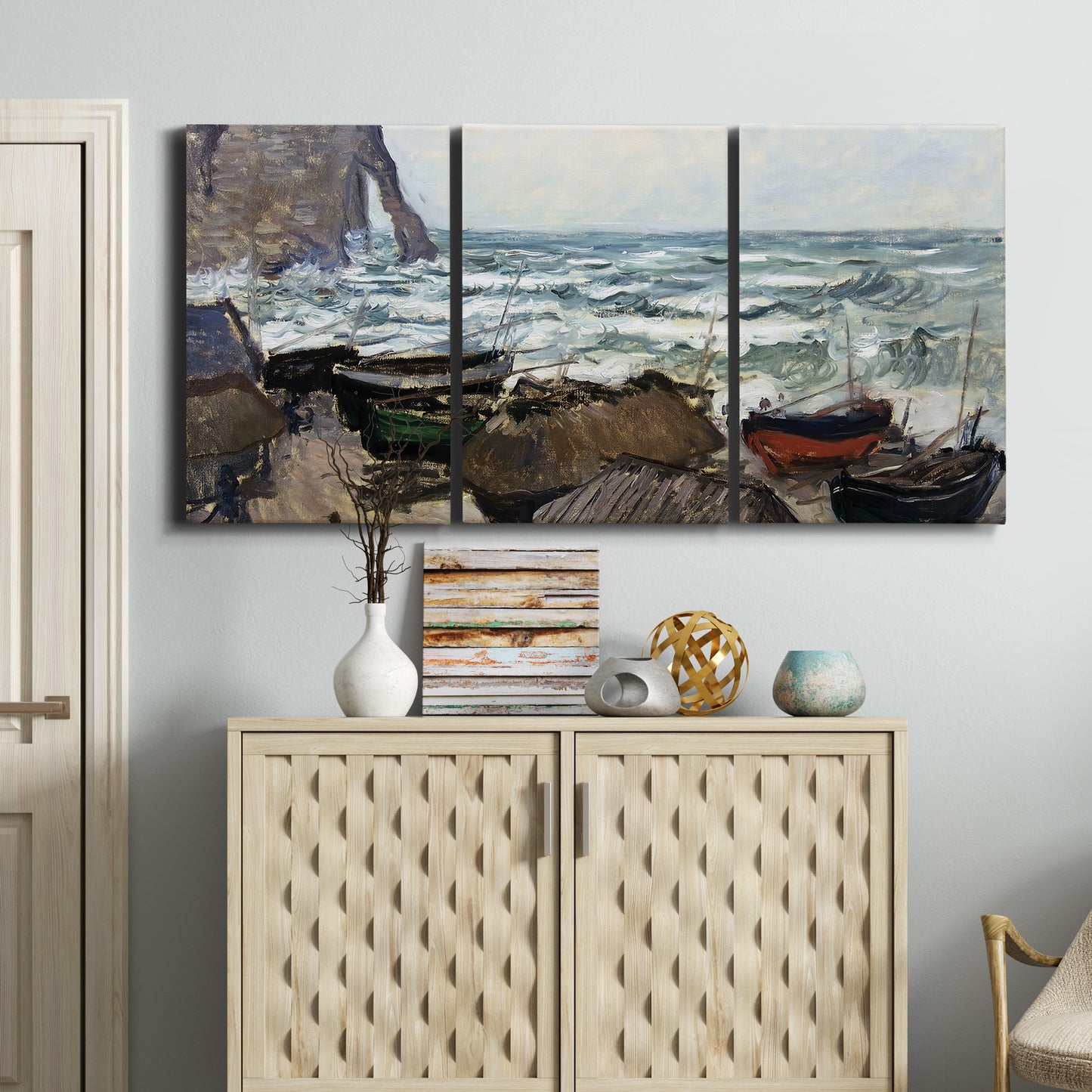 Three-panel canvas wall art featuring rough coastal seas under storm clouds, displayed above a cabinet in an entryway.