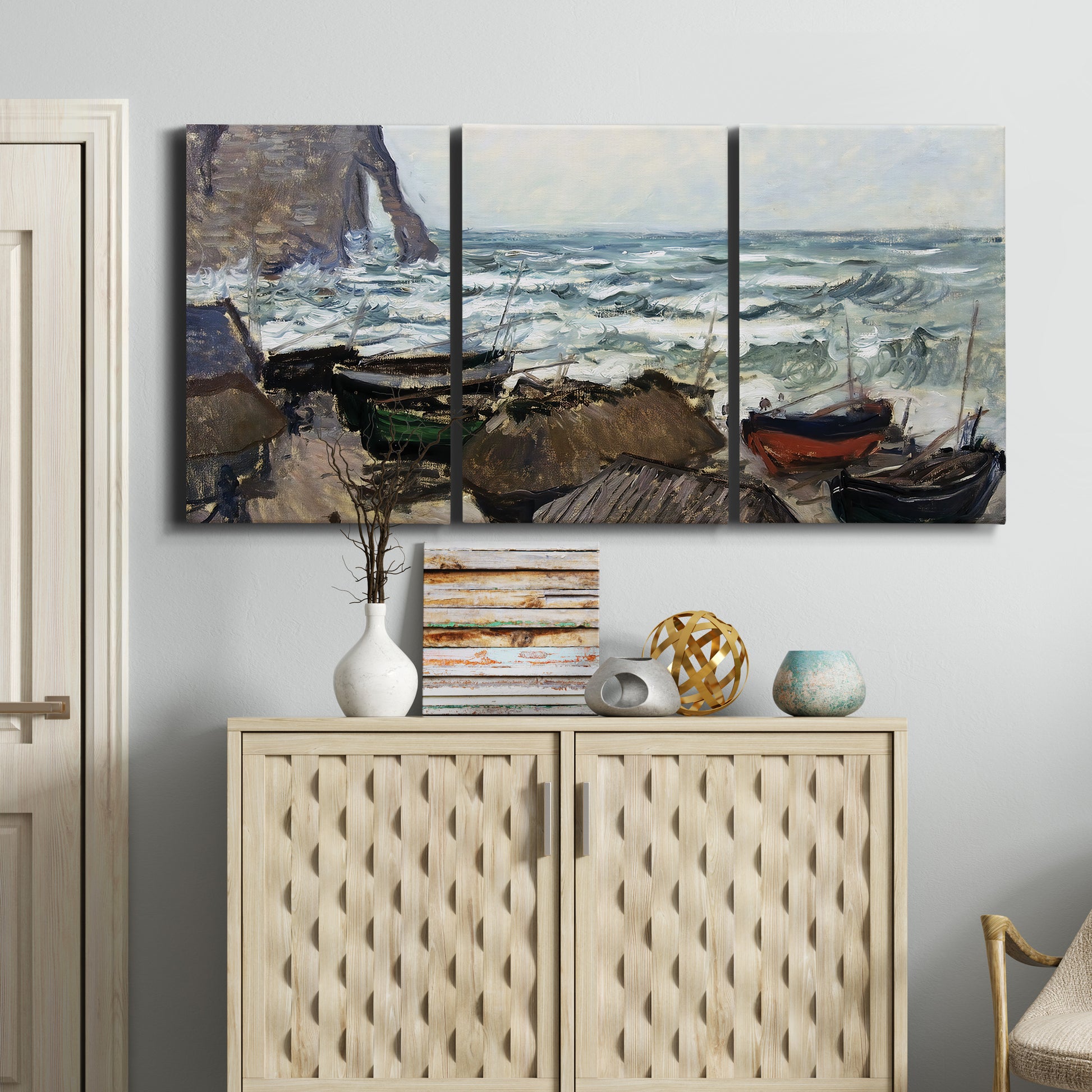 Three-panel canvas wall art featuring rough coastal seas under storm clouds, displayed above a cabinet in an entryway.