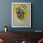 Expressive skull study painting by Vincent van Gogh in an ornate weathered white frame displayed in a dark-toned interior setting.