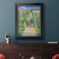 Impressionist garden landscape painting by Claude Monet in an ornate black frame with gilded inner detail displayed in a dark-toned interior setting.