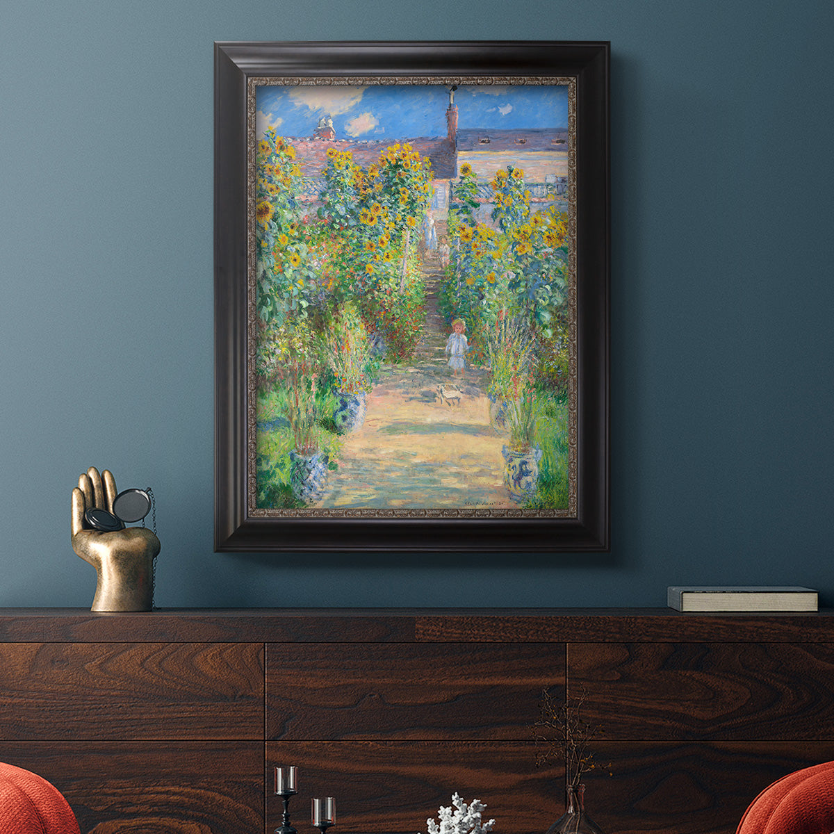 Impressionist garden landscape painting by Claude Monet in an ornate black frame with gilded inner detail displayed in a dark-toned interior setting.