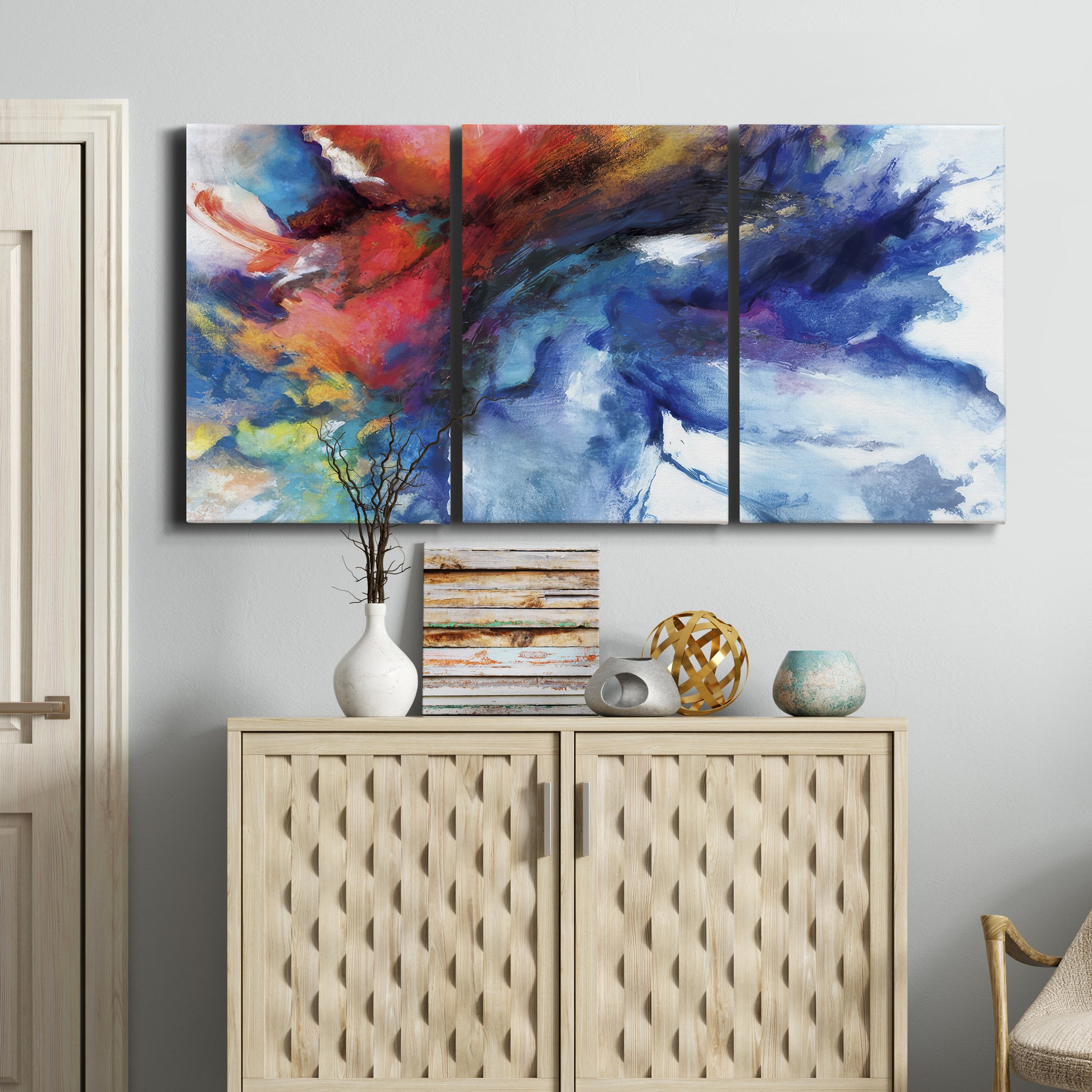 Three-panel canvas wall art featuring vibrant abstract color explosion, displayed above a cabinet in an entryway.
