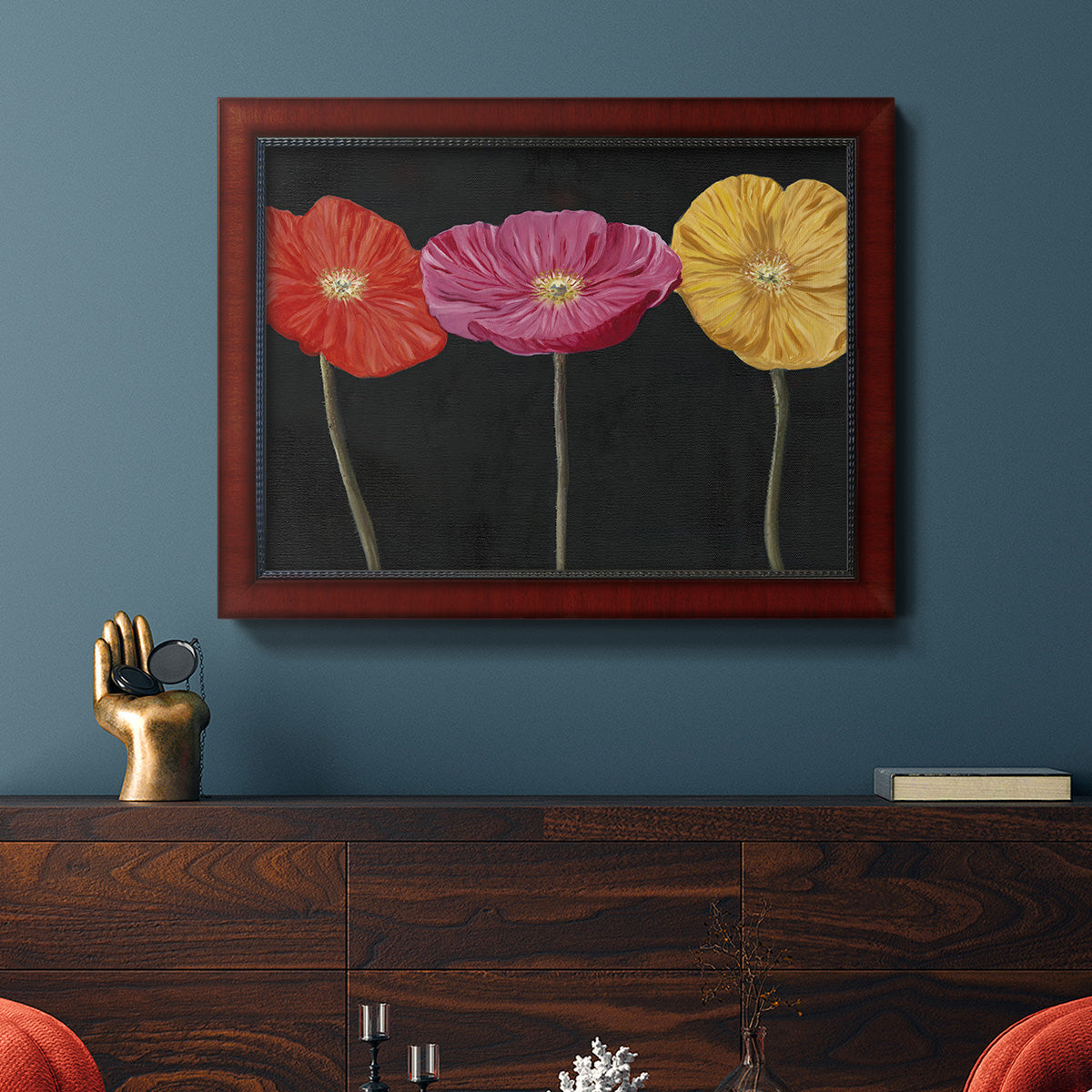 Contemporary poppy flower artwork in an ornate cherry burl wood frame displayed in a dark-toned interior setting.