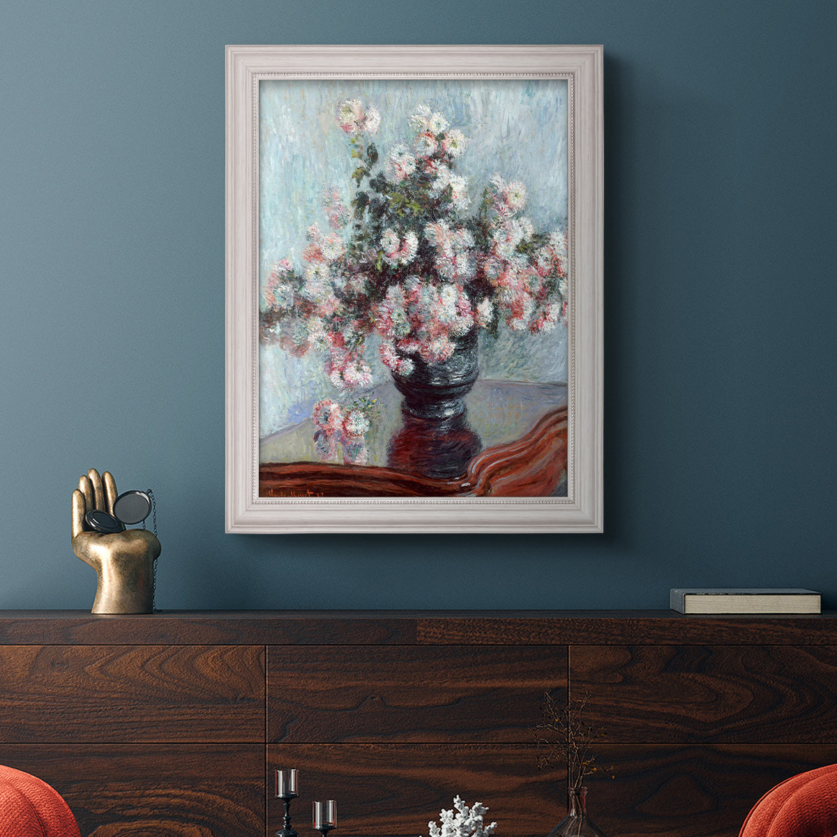 Impressionist chrysanthemum floral painting by Claude Monet in an ornate weathered white frame displayed in a dark-toned interior setting.