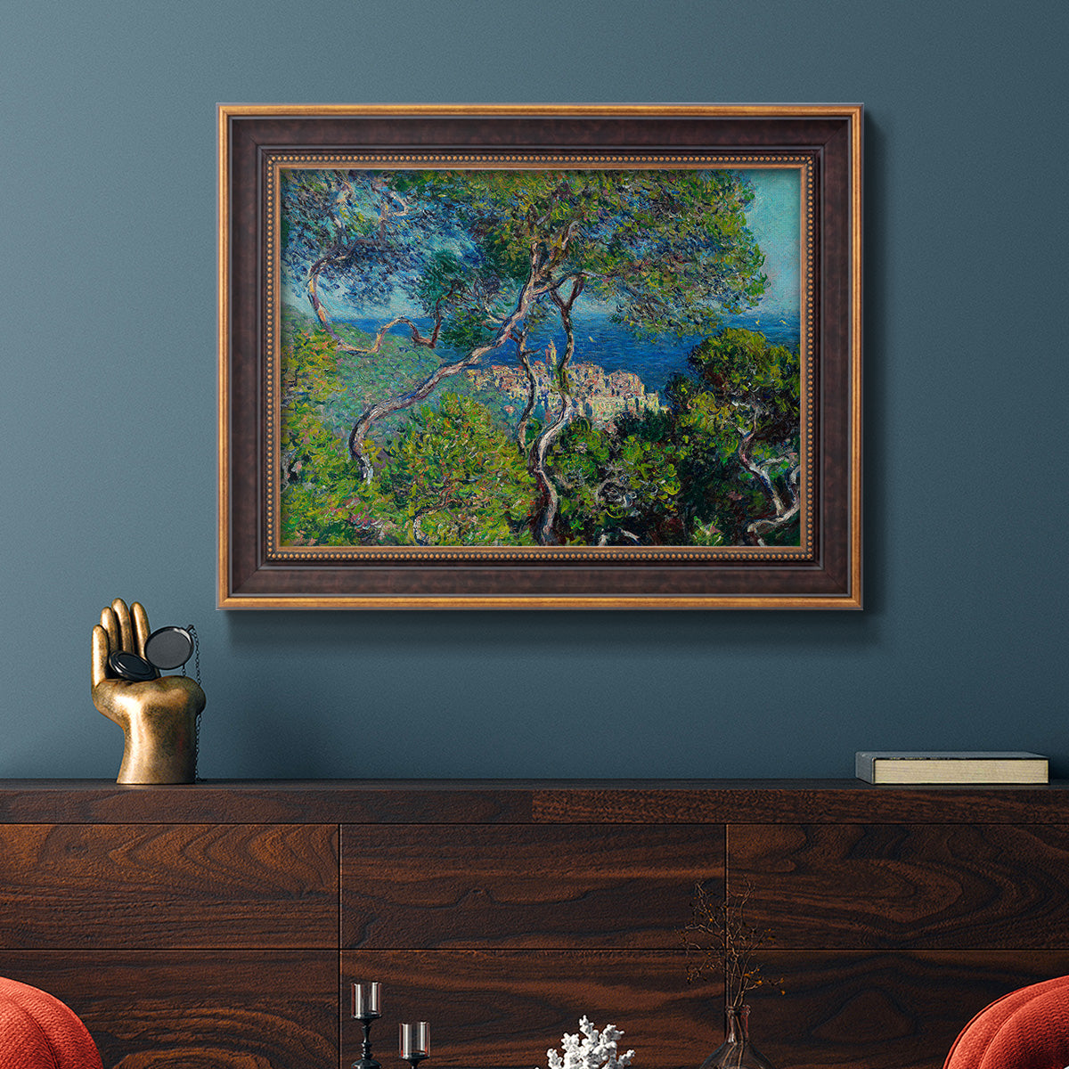 Impressionist Mediterranean coastal landscape by Claude Monet in an ornate bronzed mahogany wood frame displayed in a dark-toned interior setting.
