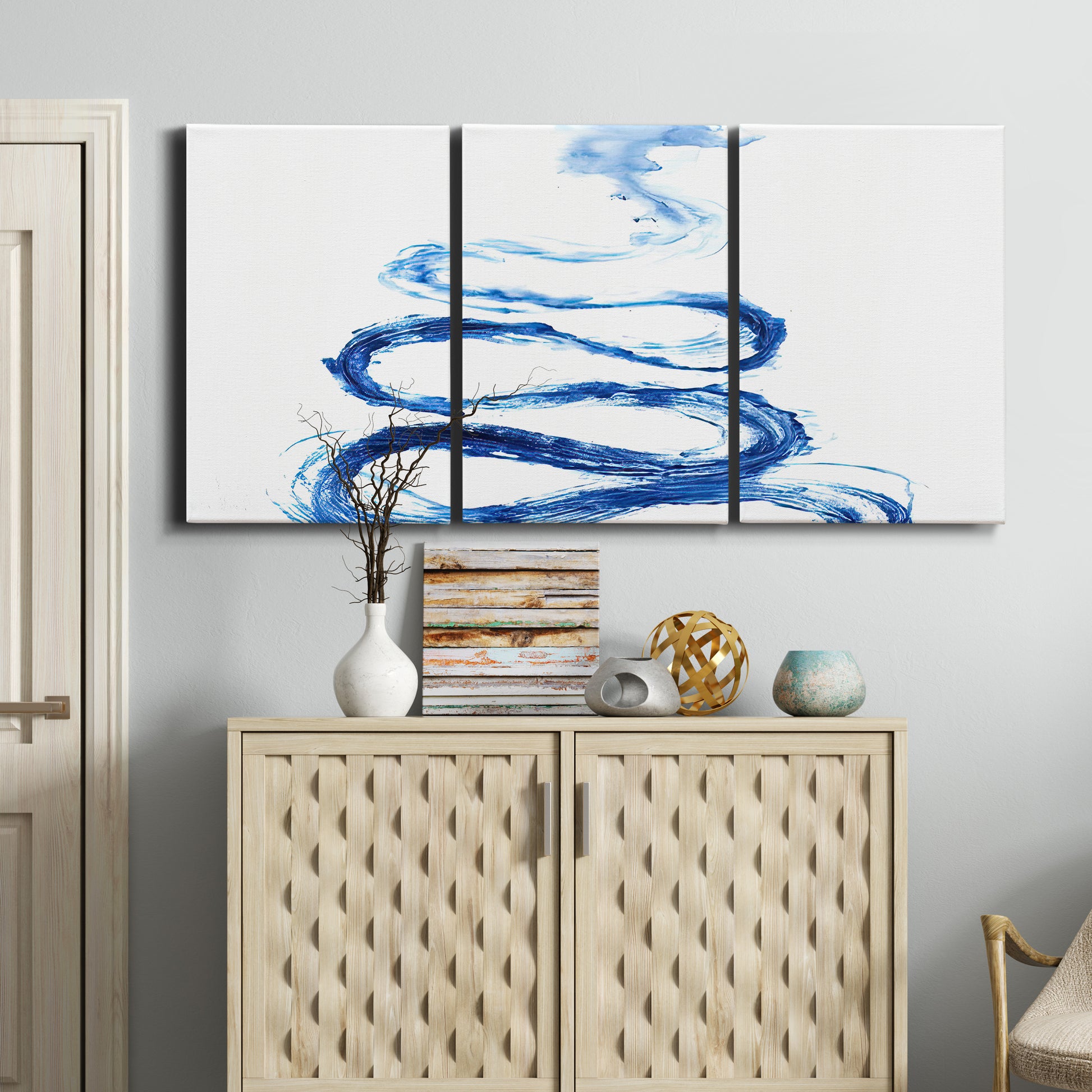 Three-panel canvas wall art featuring indigo abstract vapor watercolor, displayed above a cabinet in an entryway.