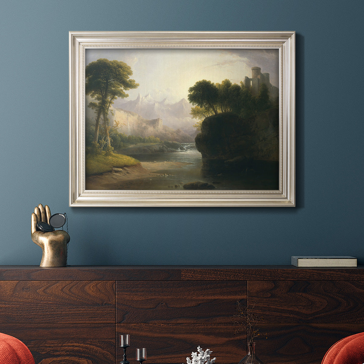 Romantic autumn landscape along the Hudson River by Thomas Doughty in an ornate champagne frame displayed in a dark-toned interior setting.