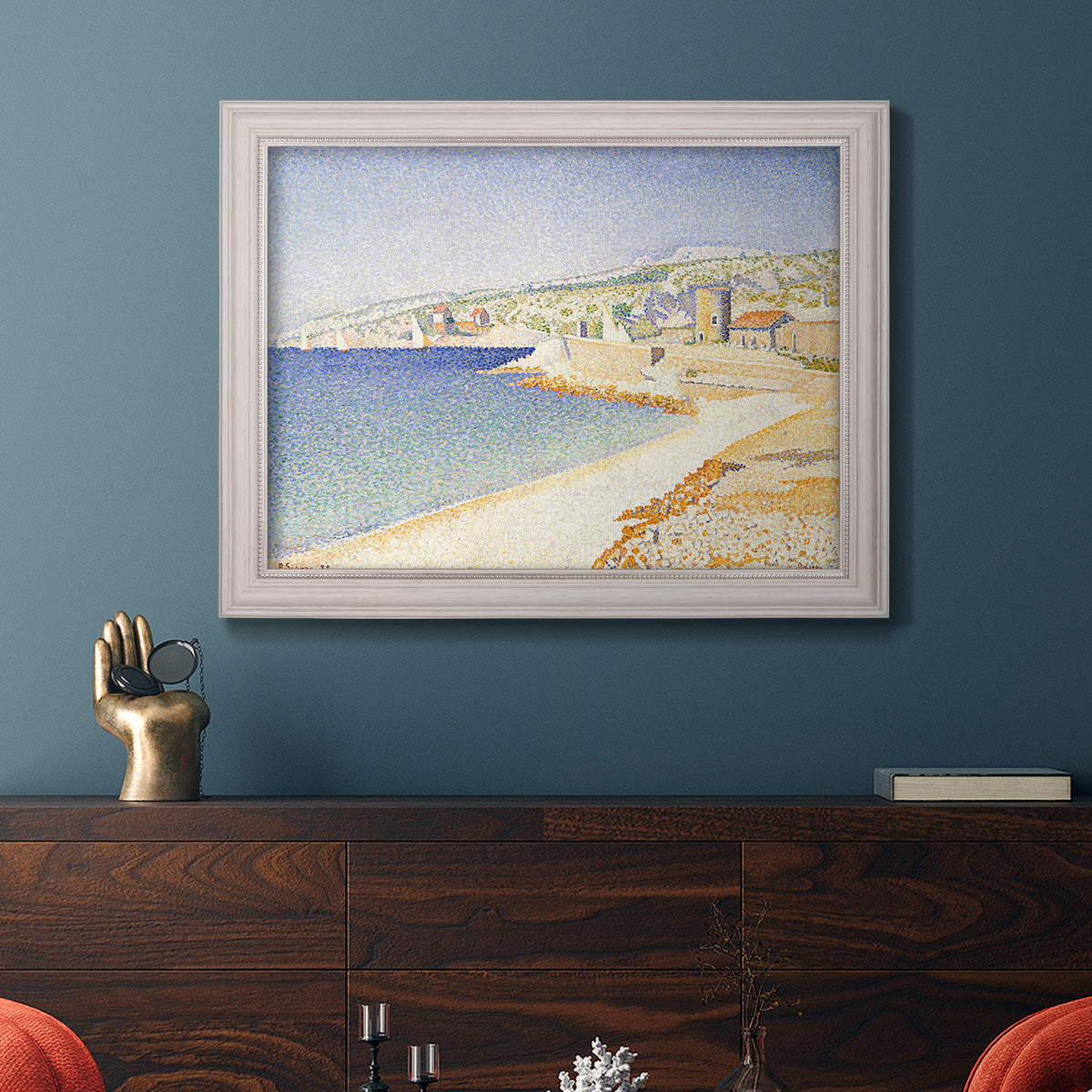 Impressionist Mediterranean jetty seascape by Paul Signac in an ornate weathered white frame displayed in a dark-toned interior setting.