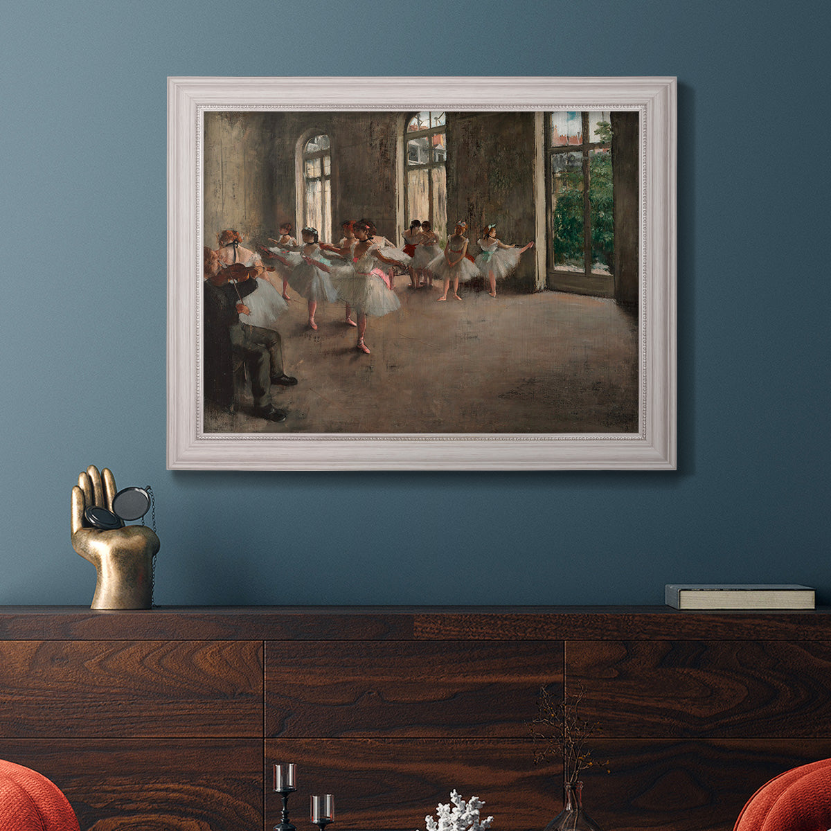 Early impressionist ballet rehearsal painting by Edgar Degas in an ornate weathered white frame displayed in a dark-toned interior setting.
