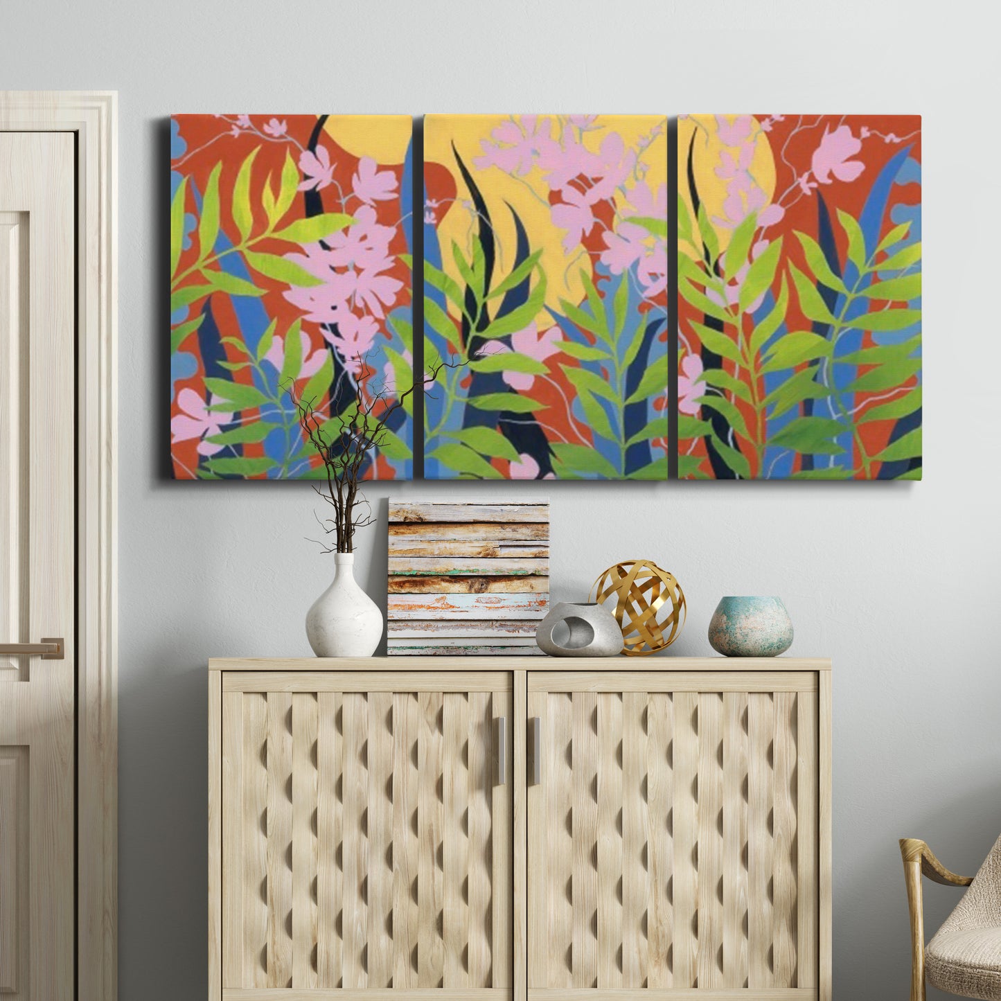 Three-panel canvas wall art featuring bold colorful floral abstraction, displayed above a cabinet in an entryway.