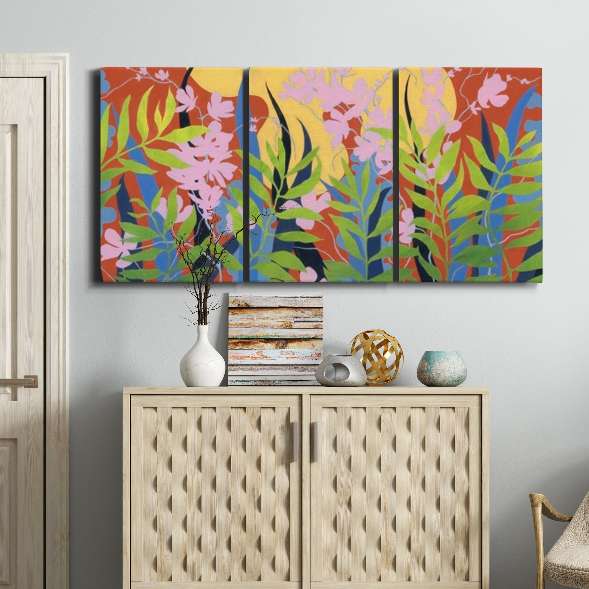 Three-panel canvas wall art featuring bold colorful floral abstraction, displayed above a cabinet in an entryway.