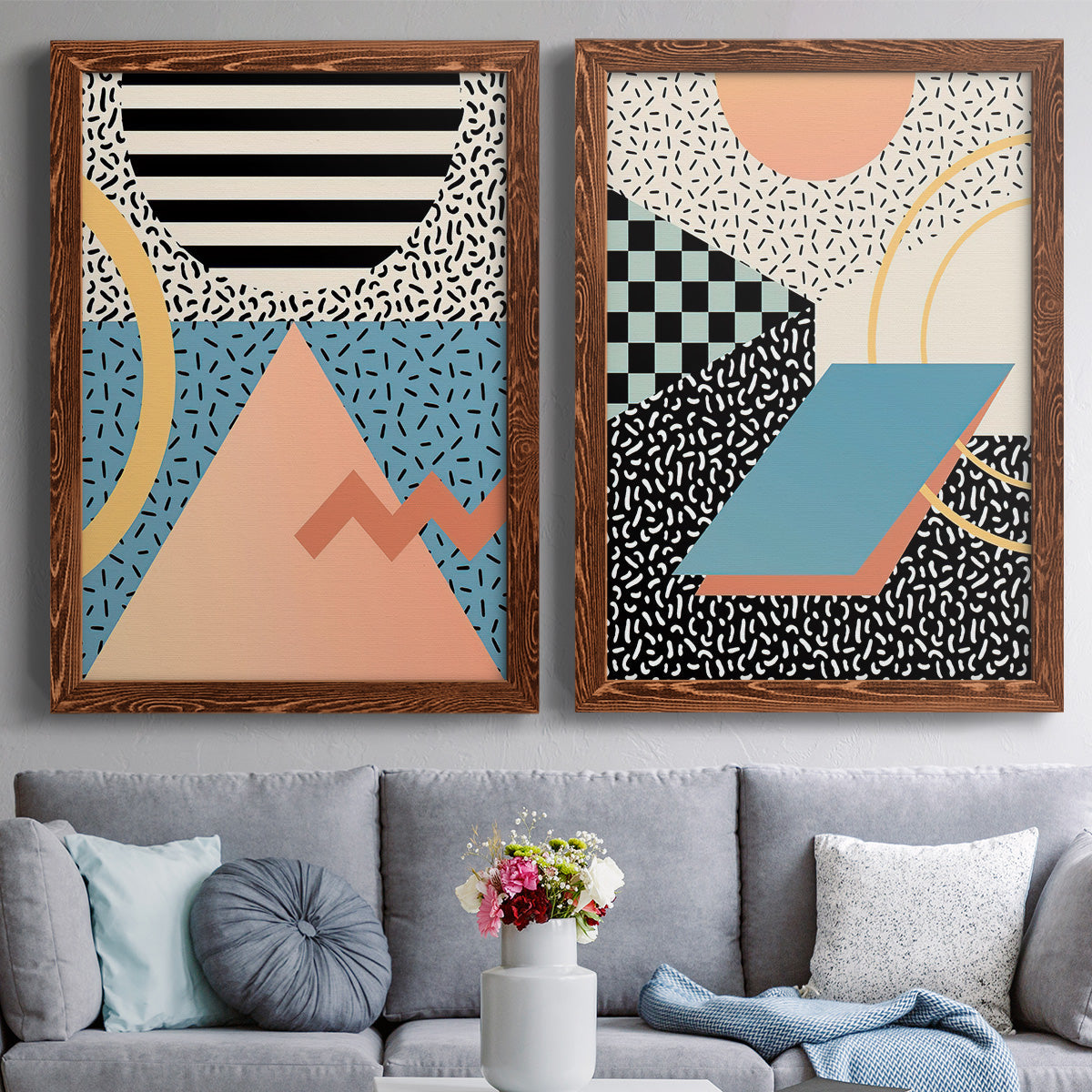 Set of two maple barnwood framed canvas prints depicting paired retro graphic abstracts with checkerboards stripes squiggles peach blue black and mint shapes above a sofa in a contemporary living room.