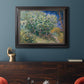 Impressionist lilac flower painting by Vincent van Gogh in an ornate black frame with gilded inner detail displayed in a dark-toned interior setting.