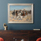 Impressionist western action scene by Frederic Remington in an ornate champagne frame displayed in a dark-toned interior setting.
