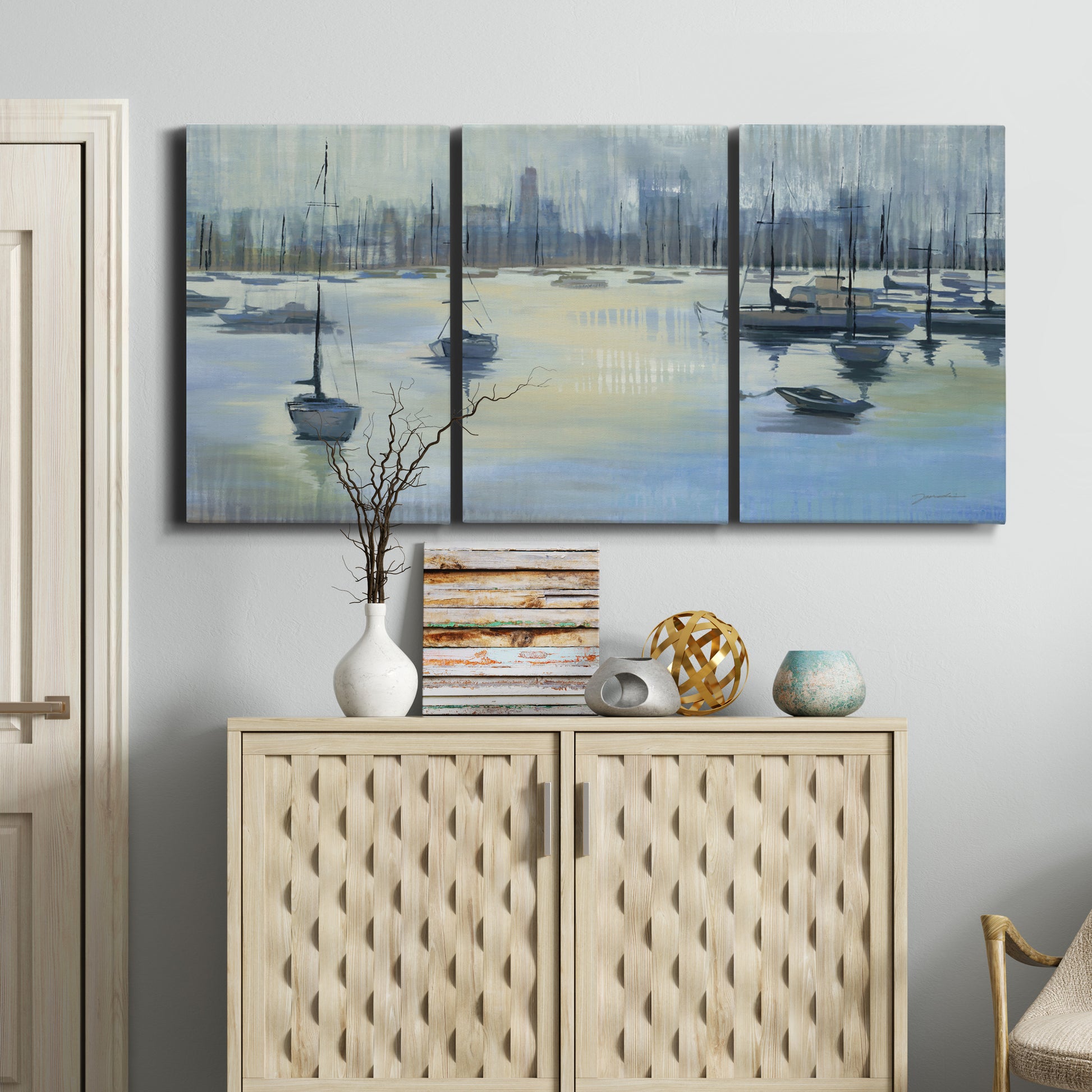Three-panel canvas wall art featuring anchored boats near shoreline, displayed above a cabinet in an entryway.