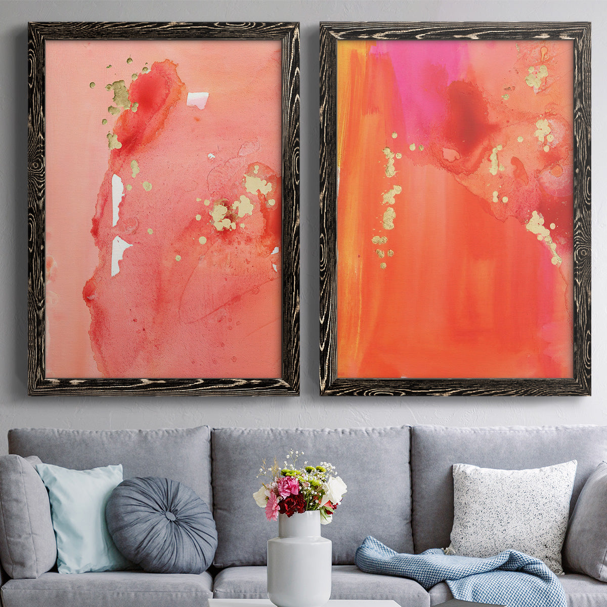 Set of two black barnwood framed canvas prints depicting paired glamorous fluid abstracts with translucent warm washes, drips, and scattered metallic accents above a sofa in a contemporary living room.