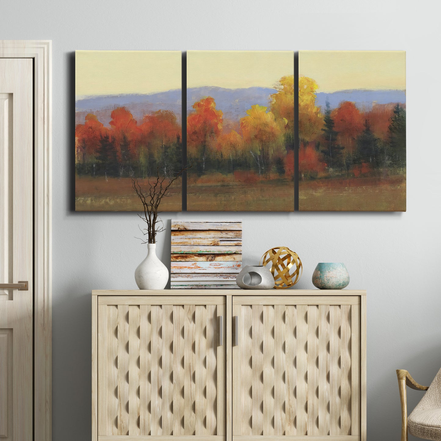 Three-panel canvas wall art featuring autumn landscape changing foliage, displayed above a cabinet in an entryway.