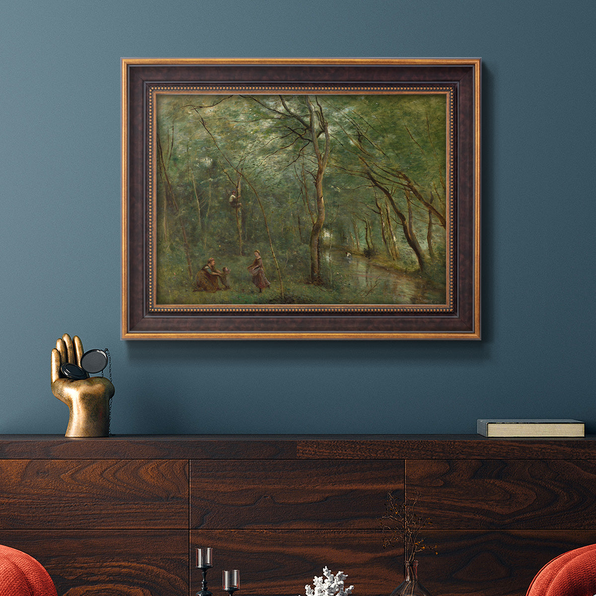 Traditional rural landscape scene with figures by Jean-Baptiste-Camille Corot in an ornate bronzed mahogany wood frame displayed in a dark-toned interior setting.