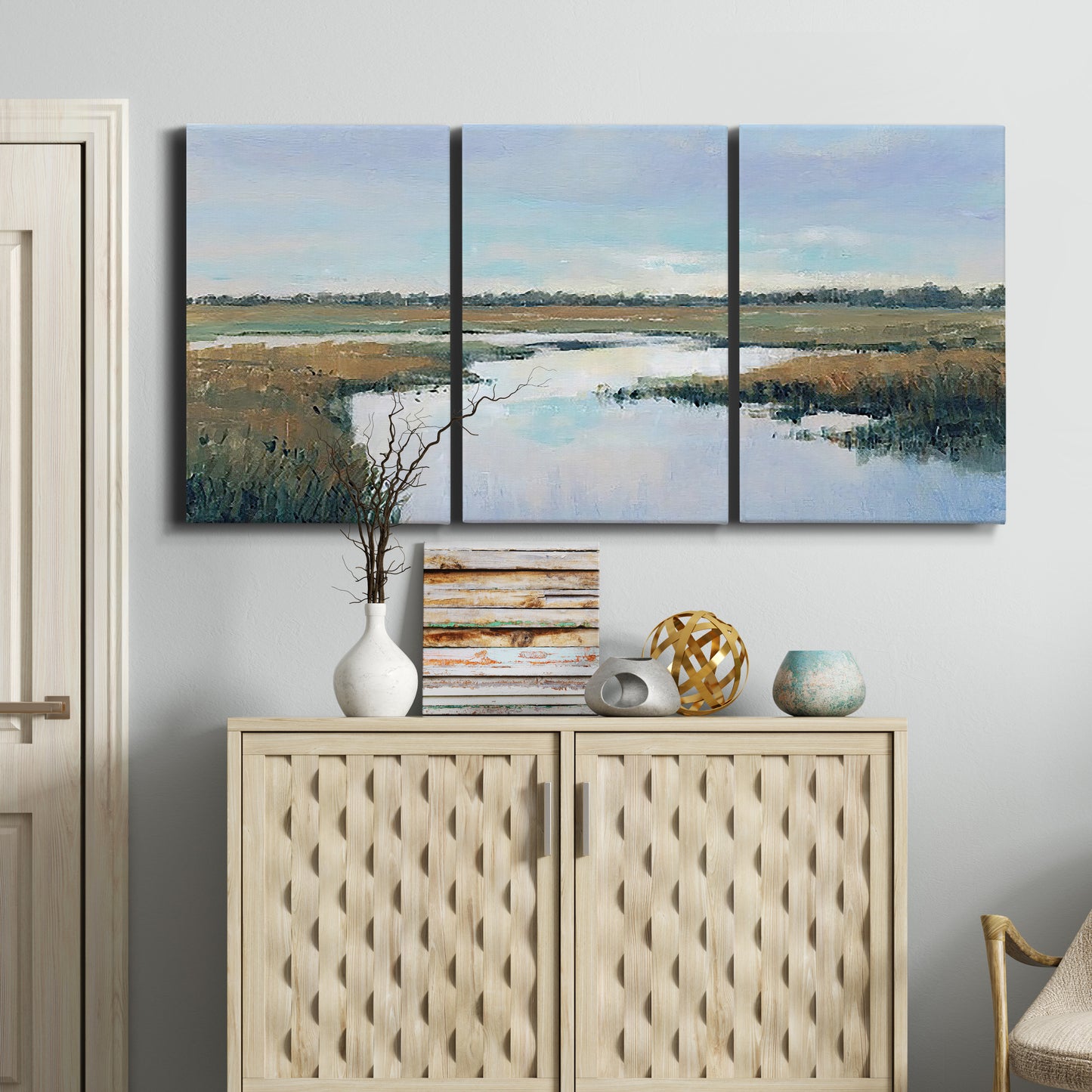 Three-panel canvas wall art featuring coastal plain meeting open water, displayed above a cabinet in an entryway.