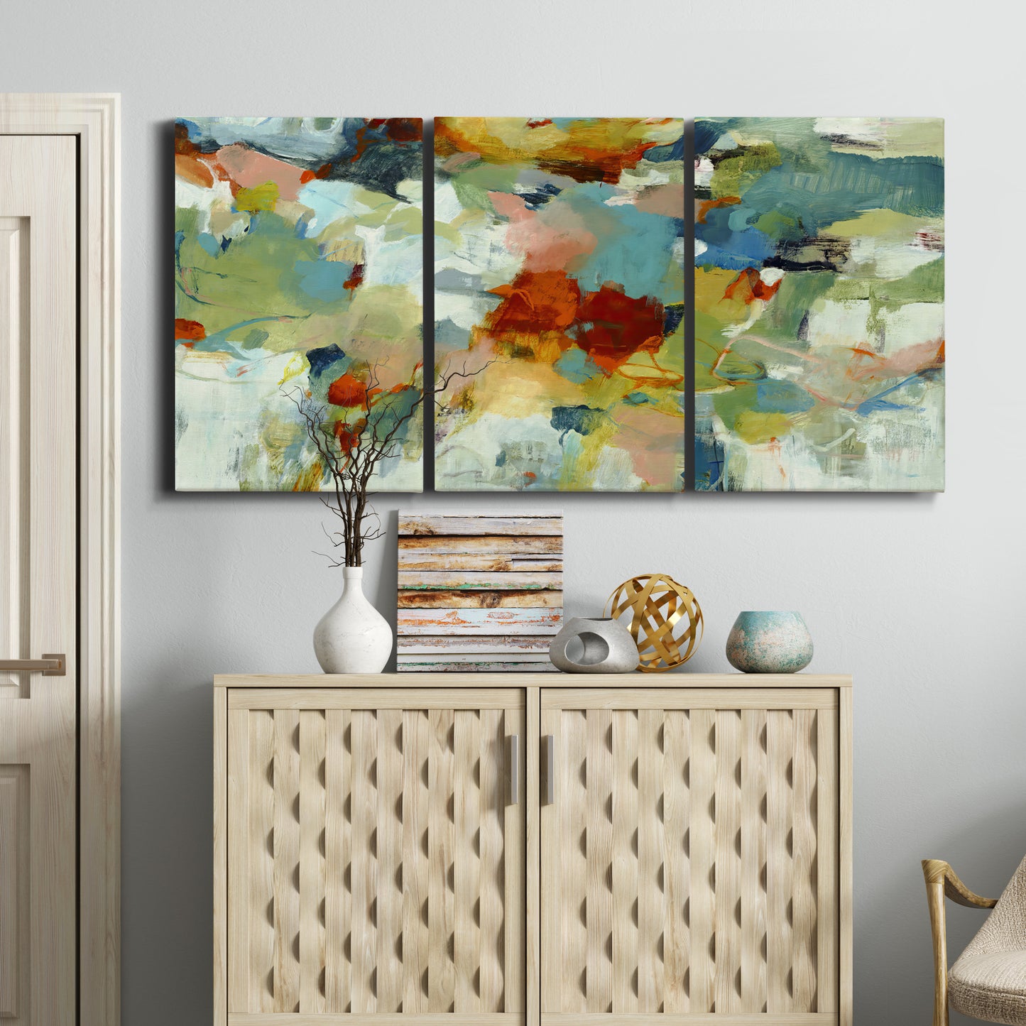 Three-panel canvas wall art featuring celebratory abstract color movement, displayed above a cabinet in an entryway.