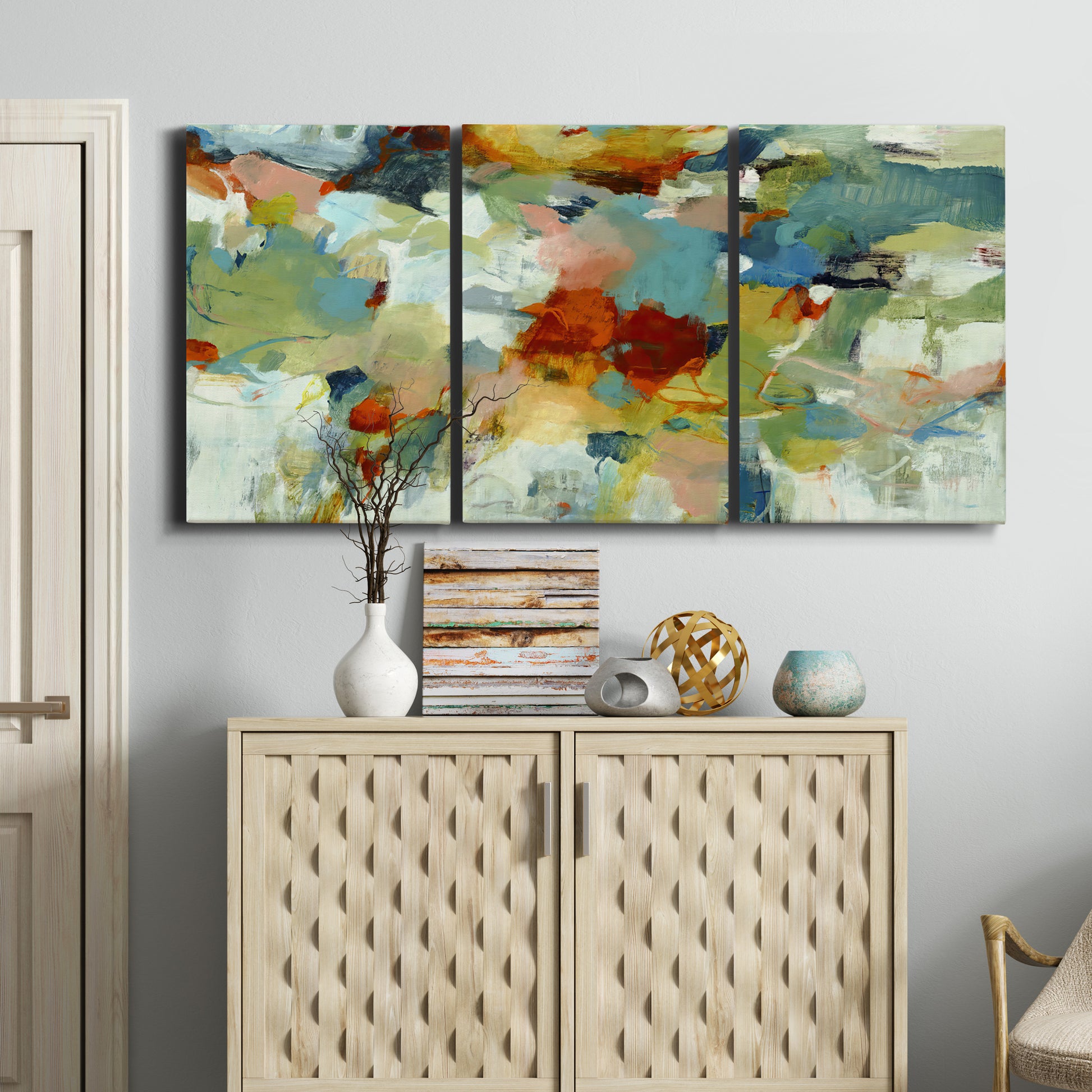 Three-panel canvas wall art featuring celebratory abstract color movement, displayed above a cabinet in an entryway.