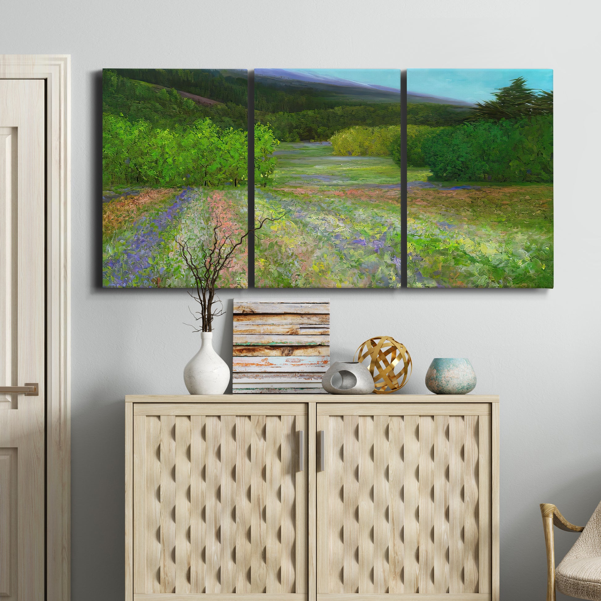 Three-panel canvas wall art featuring fresh spring meadow landscape, displayed above a cabinet in an entryway.