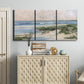 Three-panel canvas wall art featuring soft morning light over calm sea, displayed above a cabinet in an entryway.