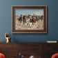 Impressionist western action scene by Frederic Remington in an ornate bronzed mahogany wood frame displayed in a dark-toned interior setting.