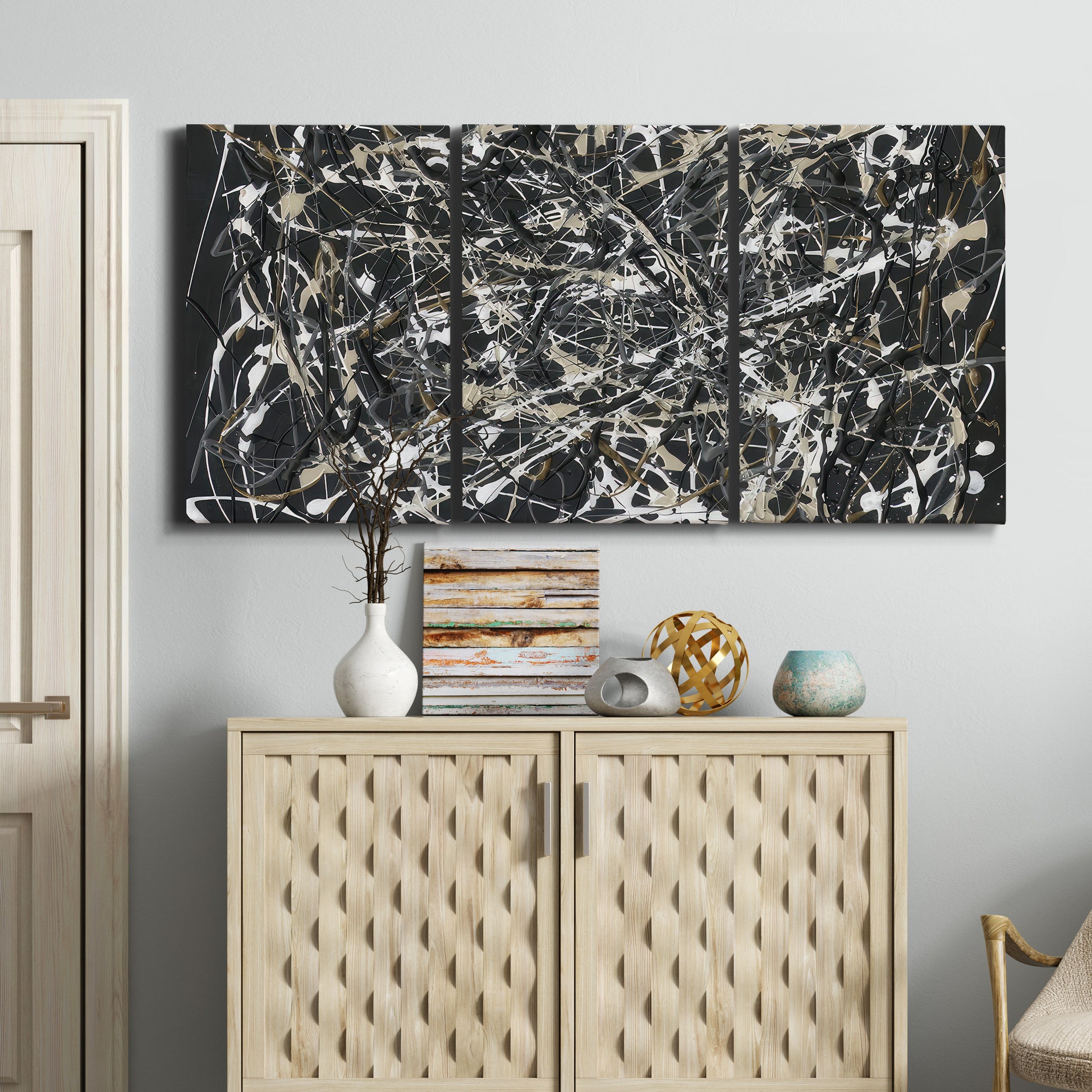 Three-panel canvas wall art featuring energetic expressionist abstract splatter, displayed above a cabinet in an entryway.