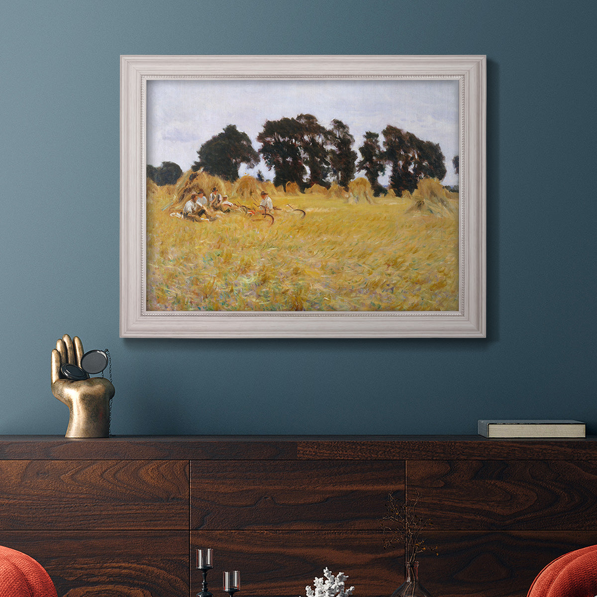Impressionist rural harvest scene by John Singer Sargent in an ornate weathered white frame displayed in a dark-toned interior setting.