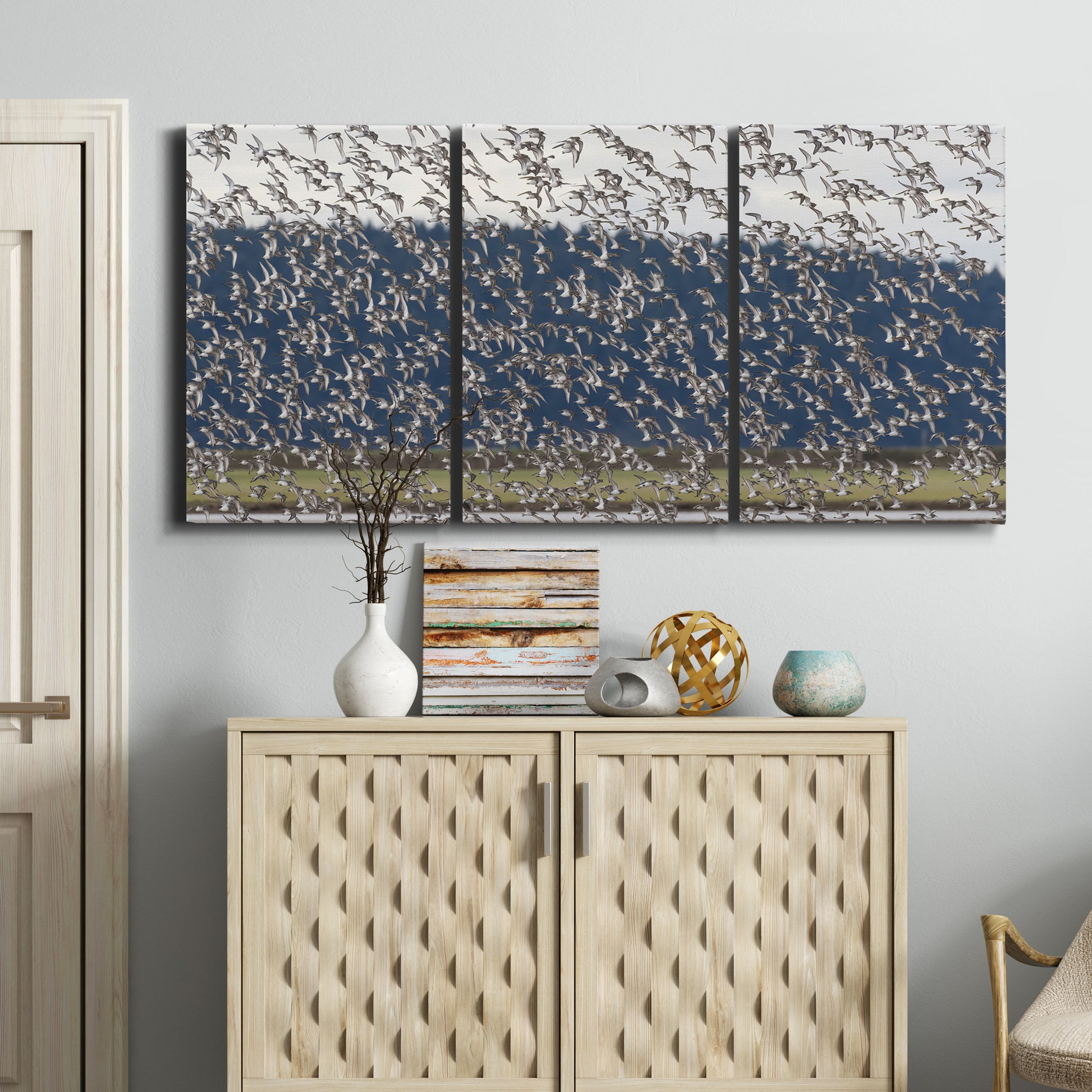 Three-panel canvas wall art featuring group of animals in open field, displayed above a cabinet in an entryway.