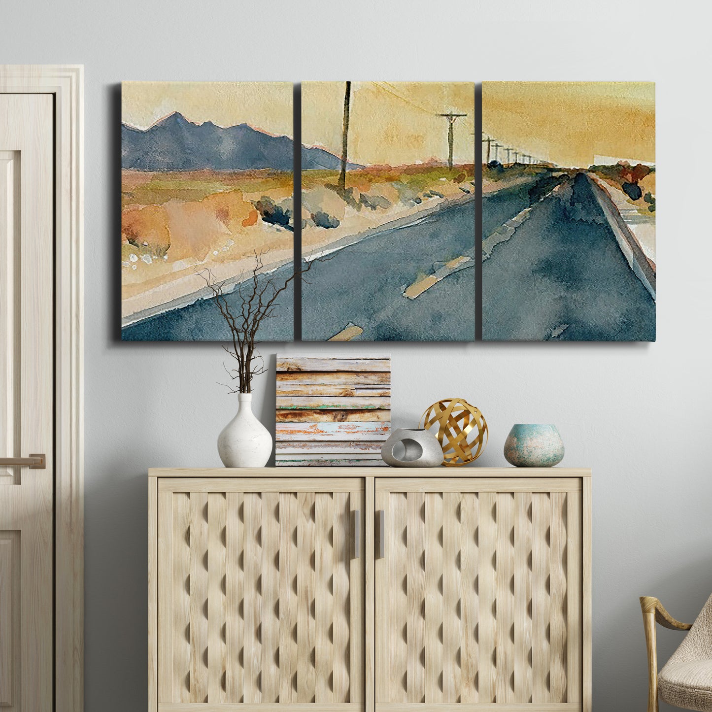 Three-panel canvas wall art featuring empty highway stretching through landscape, displayed above a cabinet in an entryway.