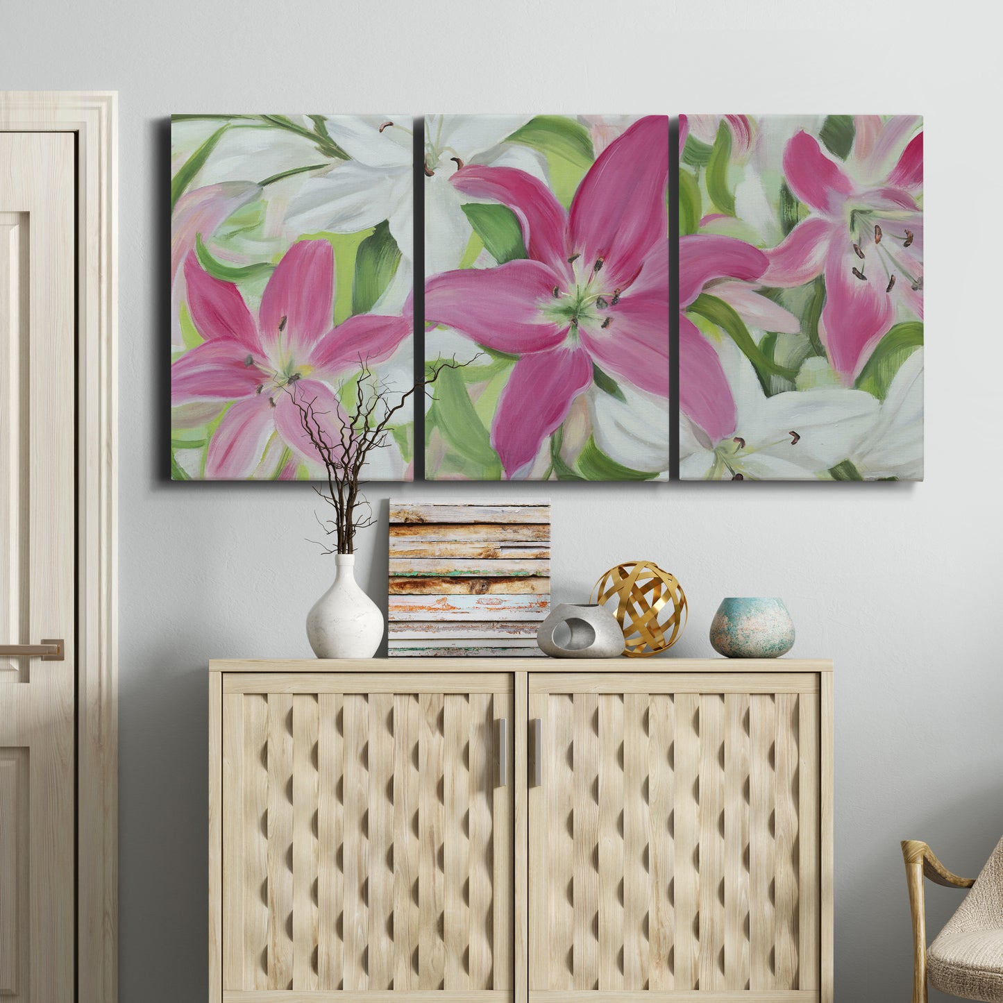 Three-panel canvas wall art featuring pink and white lilies in bloom, displayed above a cabinet in an entryway.