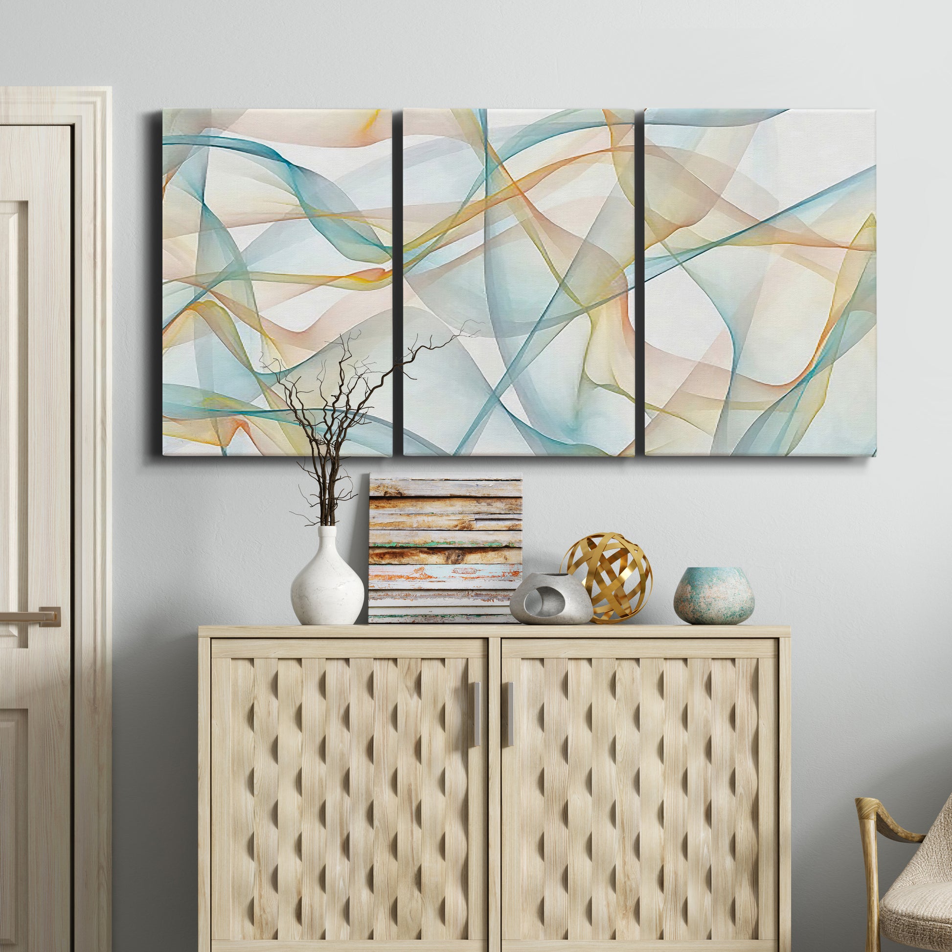 Three-panel canvas wall art featuring flowing abstract curves and wave patterns, displayed above a cabinet in an entryway.