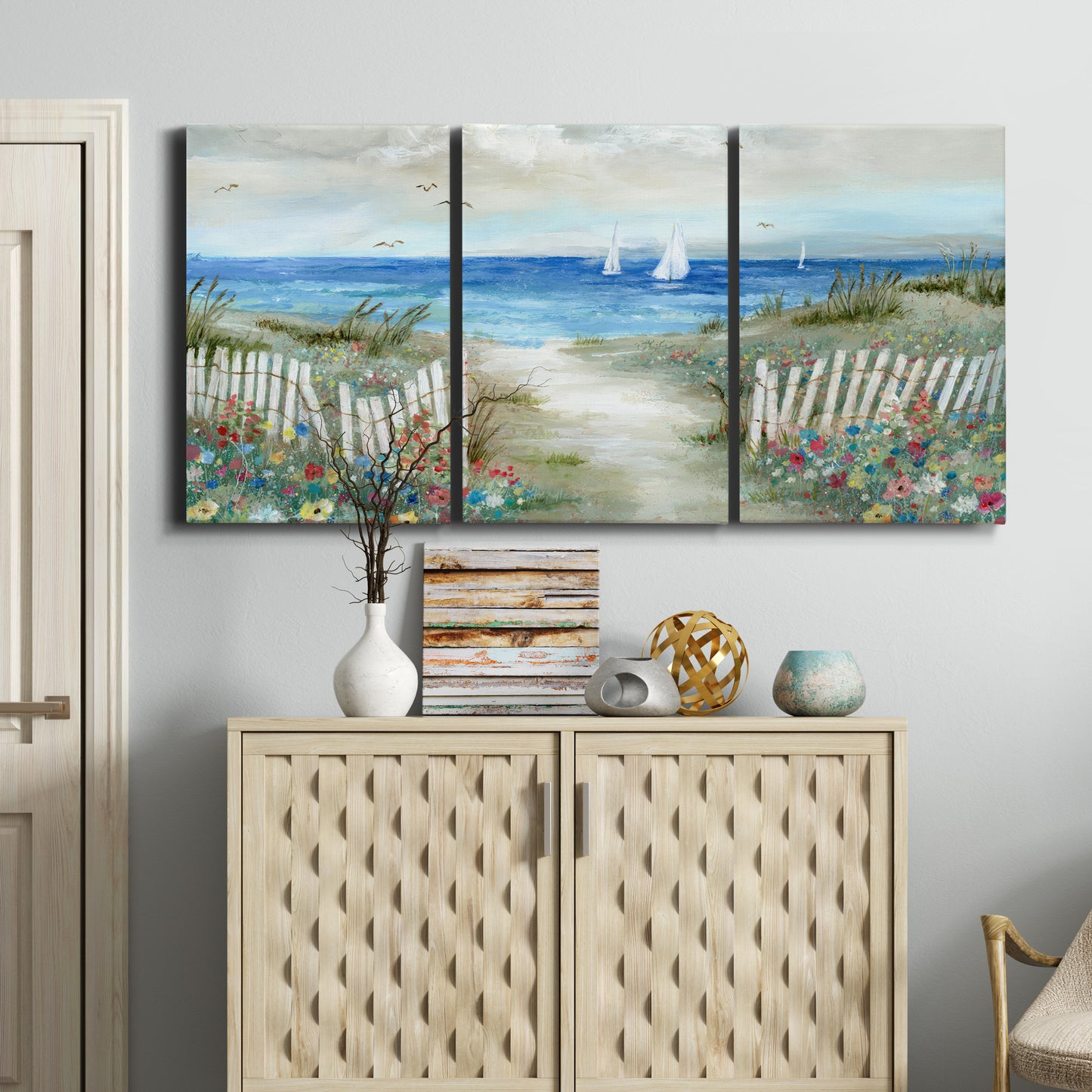Three-panel canvas wall art featuring lush coastal garden landscape, displayed above a cabinet in an entryway.