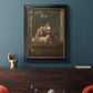 Classical genre painting of a child blowing soap bubbles by Jean-Siméon Chardin in an ornate black frame with gilded inner detail displayed in a dark-toned interior setting.