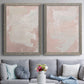 Set of two gray barnwood framed canvas prints depicting paired minimalist color-field abstracts with cloudy rose washes, broad pale strokes, and subtle texture above a sofa in a contemporary living room.