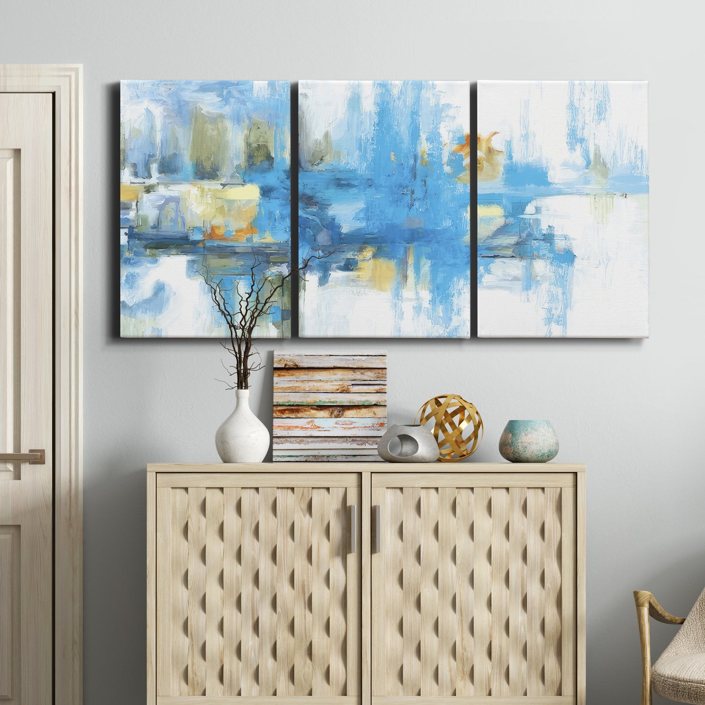 Three-panel canvas wall art featuring blue toned abstract city rhythm, displayed above a cabinet in an entryway.