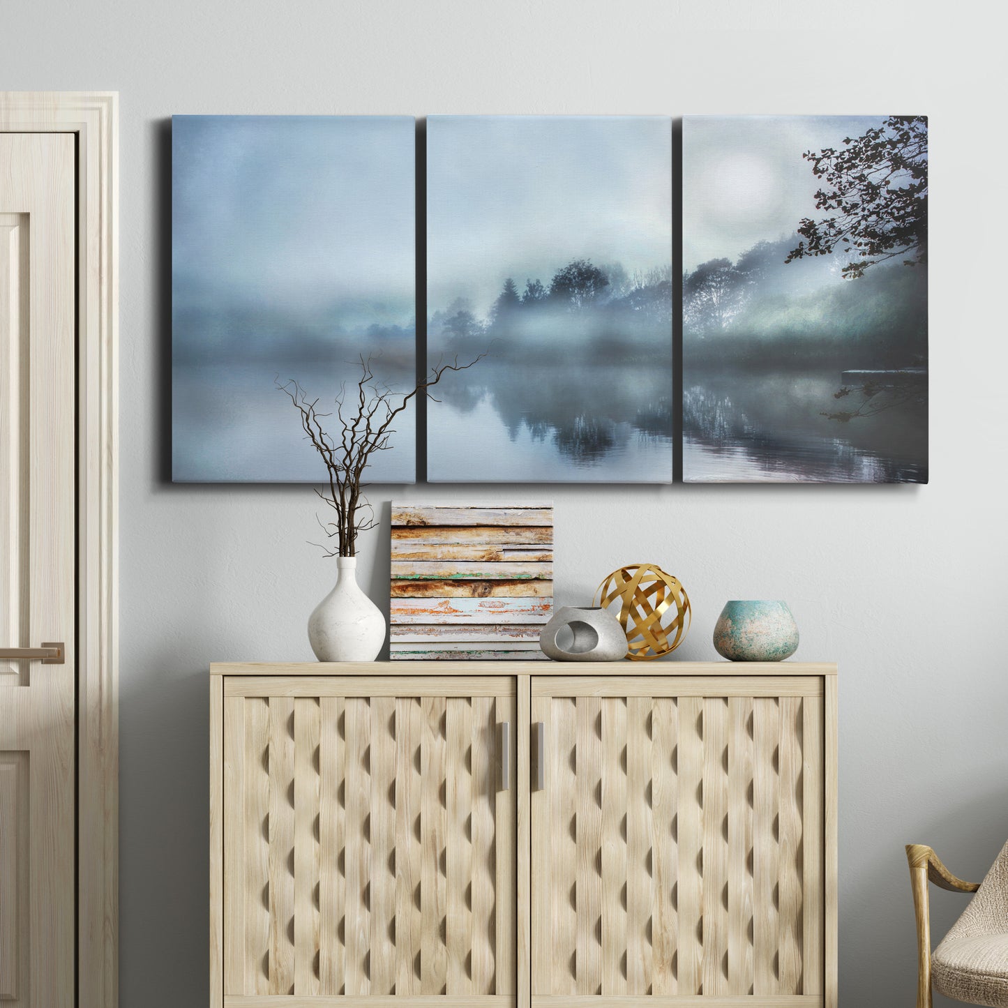 Three-panel canvas wall art featuring calm waters at sunrise photograph, displayed above a cabinet in an entryway.