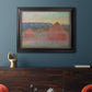 Impressionist haystack series landscape by Claude Monet in an ornate black frame with gilded inner detail displayed in a dark-toned interior setting.