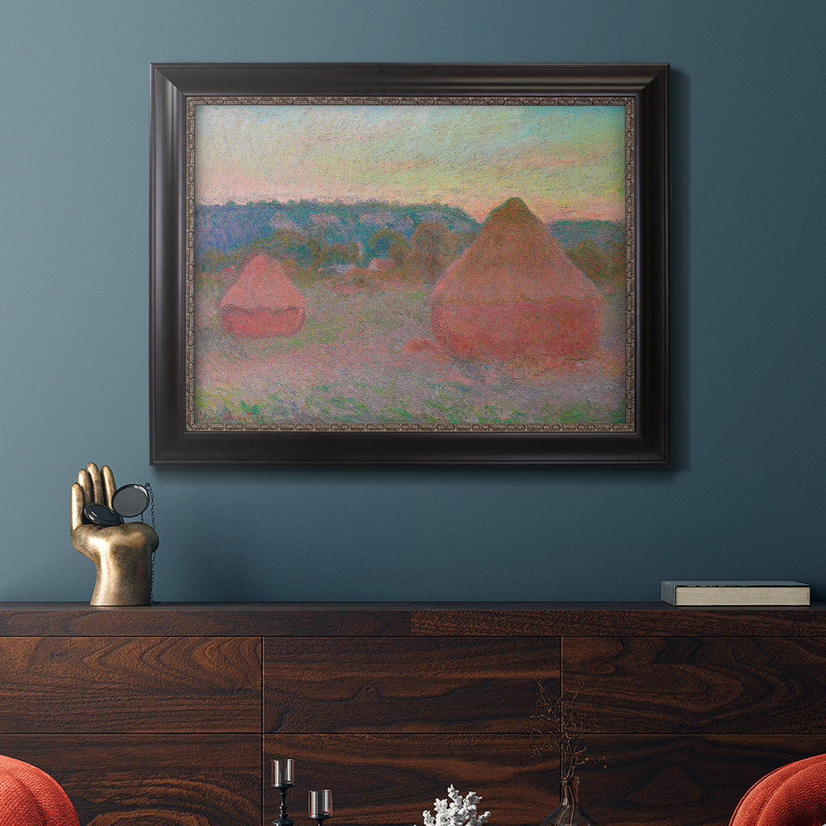 Impressionist haystack series landscape by Claude Monet in an ornate black frame with gilded inner detail displayed in a dark-toned interior setting.