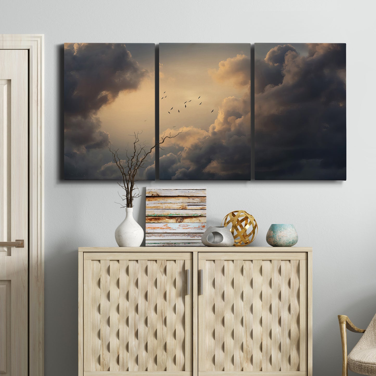 Three-panel canvas wall art featuring surreal floating figures above landscape, displayed above a cabinet in an entryway.