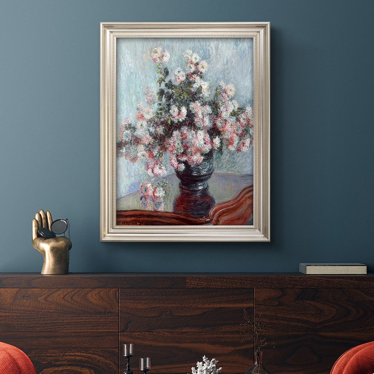 Impressionist chrysanthemum floral painting by Claude Monet in an ornate champagne frame displayed in a dark-toned interior setting.