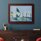 Coastal harbor watercolor painting in an ornate cherry burl wood frame displayed in a dark-toned interior setting.