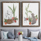 Set of two walnut barnwood framed canvas prints depicting paired whimsical botanical animal illustrations with curious felines, terracotta pots, succulents, and leafy stems above a sofa in a contemporary living room.