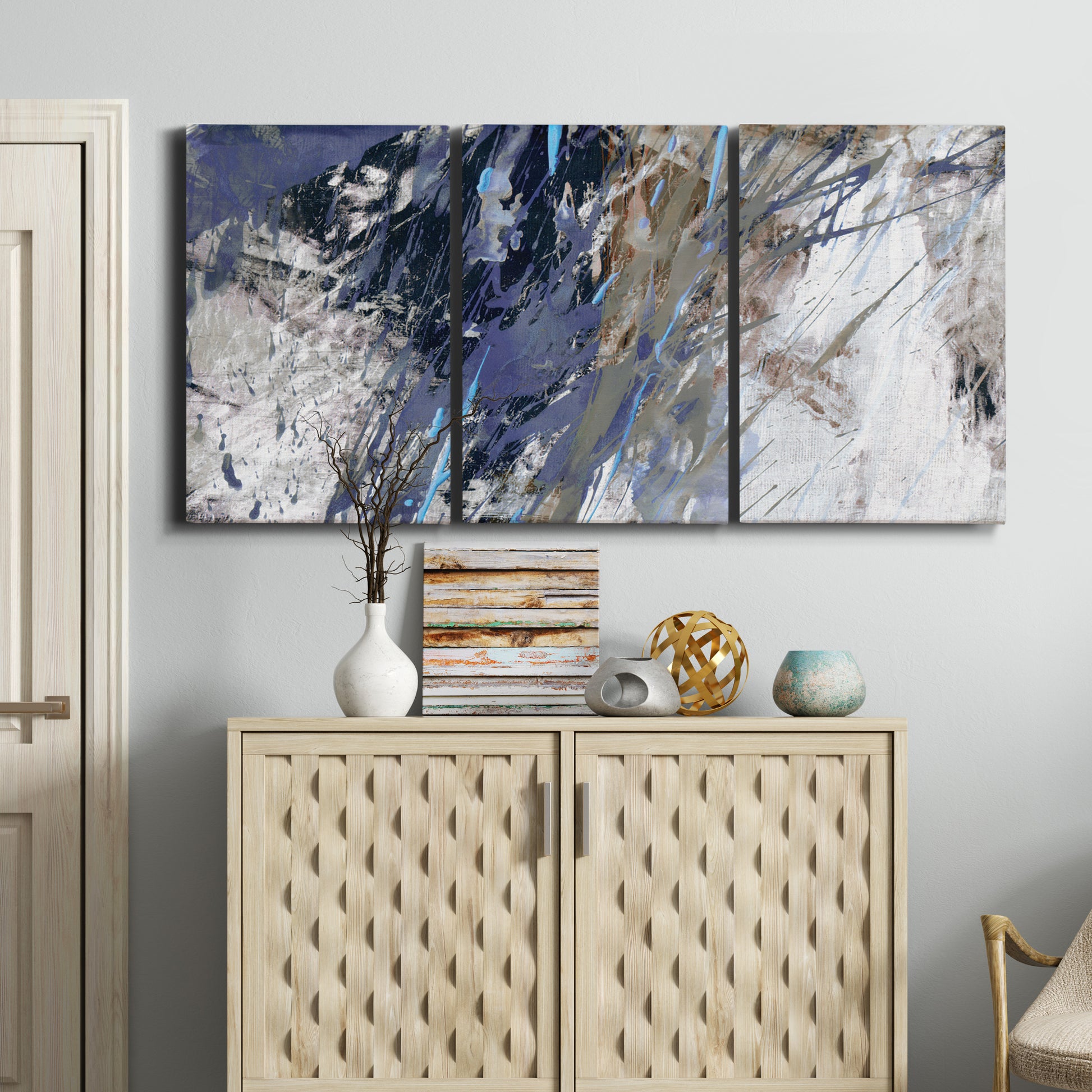 Three-panel canvas wall art featuring textured blue abstract composition, displayed above a cabinet in an entryway.