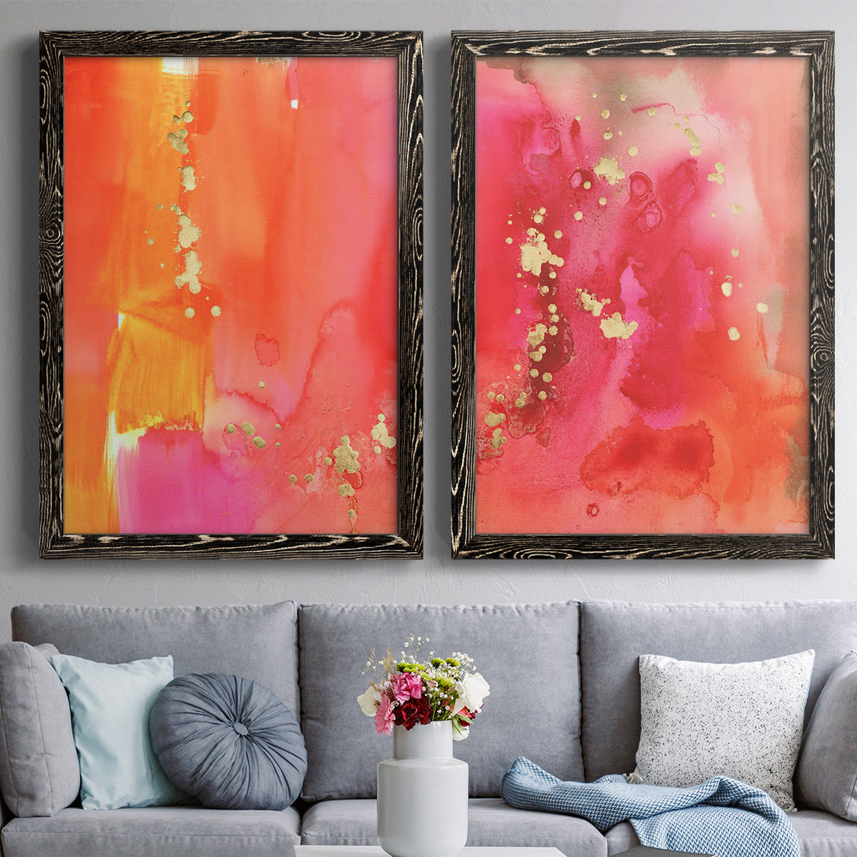 Set of two black barnwood framed canvas prints depicting paired glamorous fluid abstracts with translucent warm washes, drips, and scattered metallic accents above a sofa in a contemporary living room.