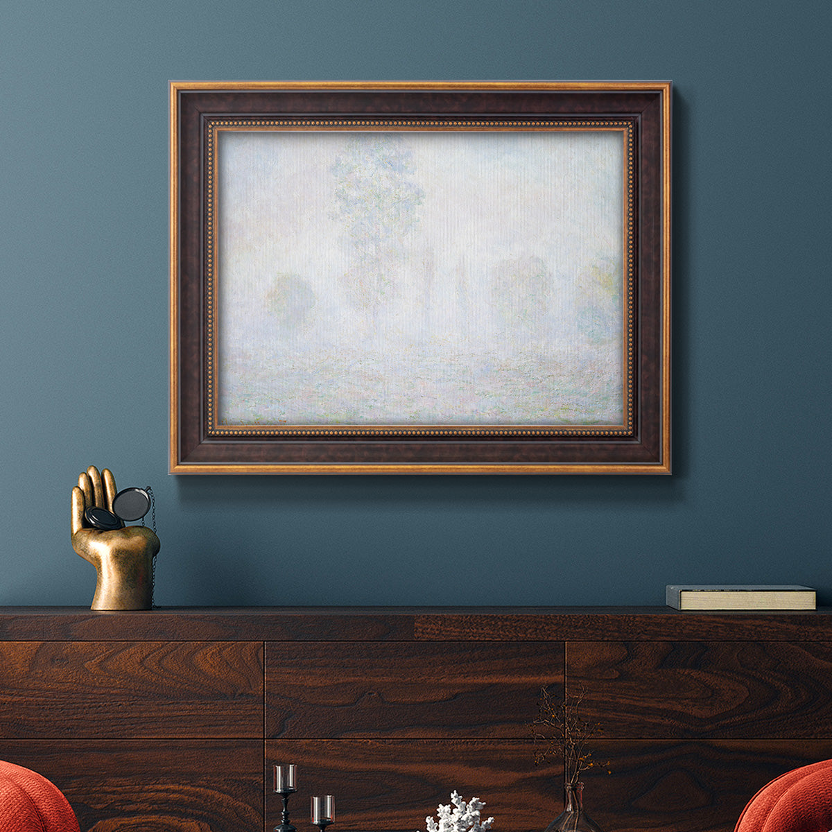 Impressionist atmospheric landscape in morning haze by Claude Monet in an ornate bronzed mahogany wood frame displayed in a dark-toned interior setting.